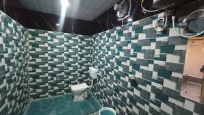 Un baño con suelo de baldosas de diseño ajedrezado, un inodoro, un bidé y una zona de ducha.