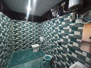 Une salle de bain avec un carrelage à motifs à carreaux, des toilettes, un bidet et un espace douche.