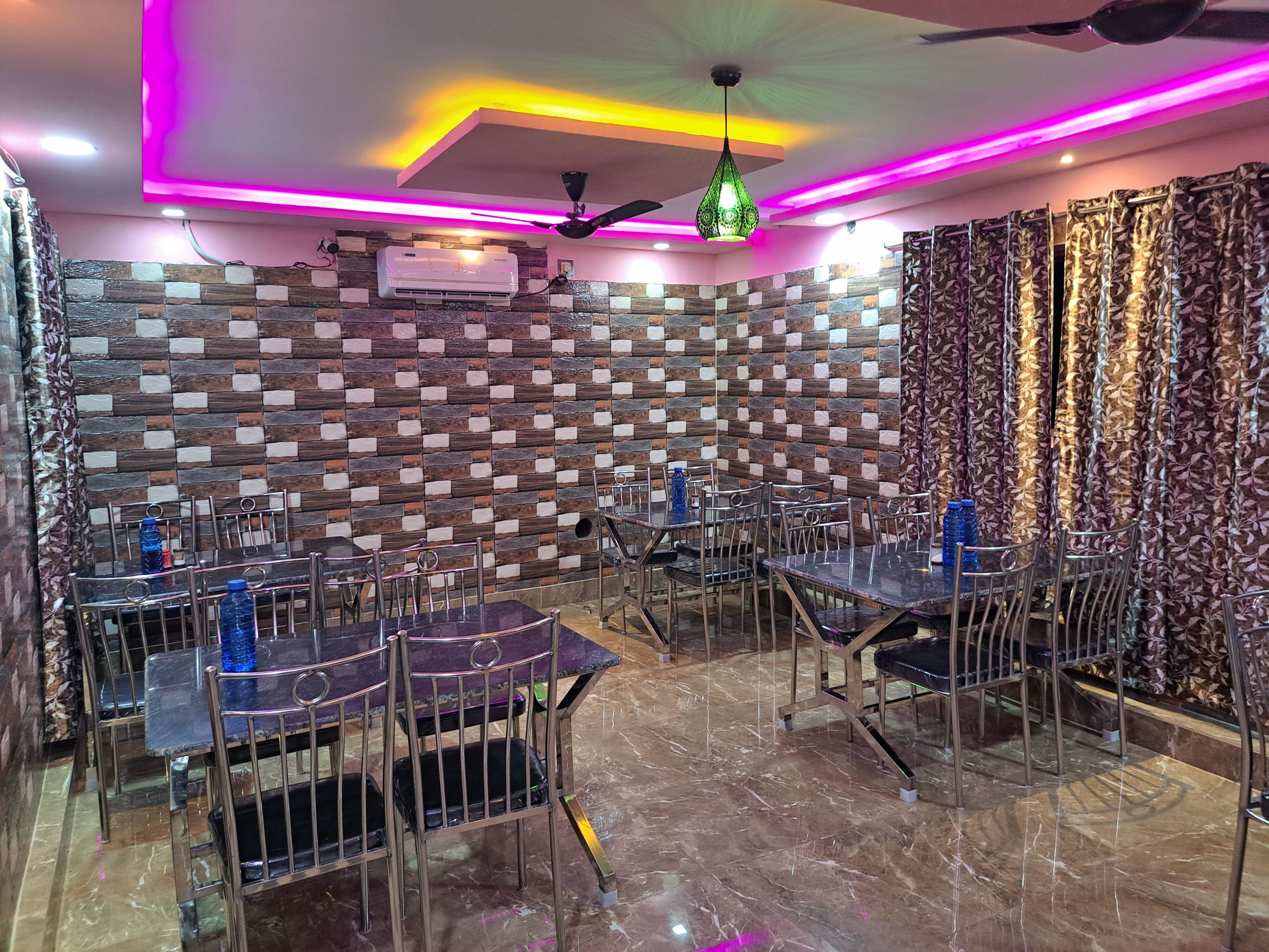 Interior de restaurante con diseño moderno, destacando una pared con estampado, suelo de mármol y sillas de metal.