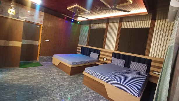 Habitación de hotel con dos camas, cabecero de madera, piso de mármol y ventilador de techo.