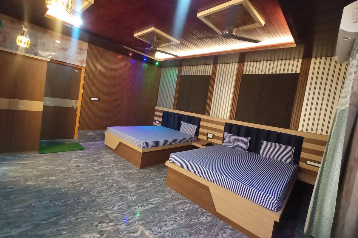 A hotel room with two beds, a wooden headboard, a marble floor, and a ceiling fan.