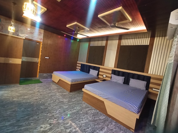 Une chambre d’hôtel avec deux lits, une tête de lit en bois, un sol en marbre et un ventilateur de plafond.