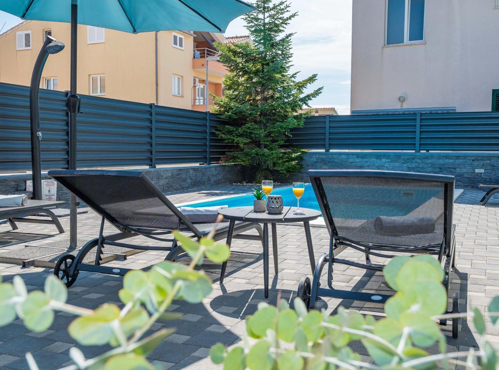 A poolside area with lounge chairs, a small table with drinks, and a Christmas tree.