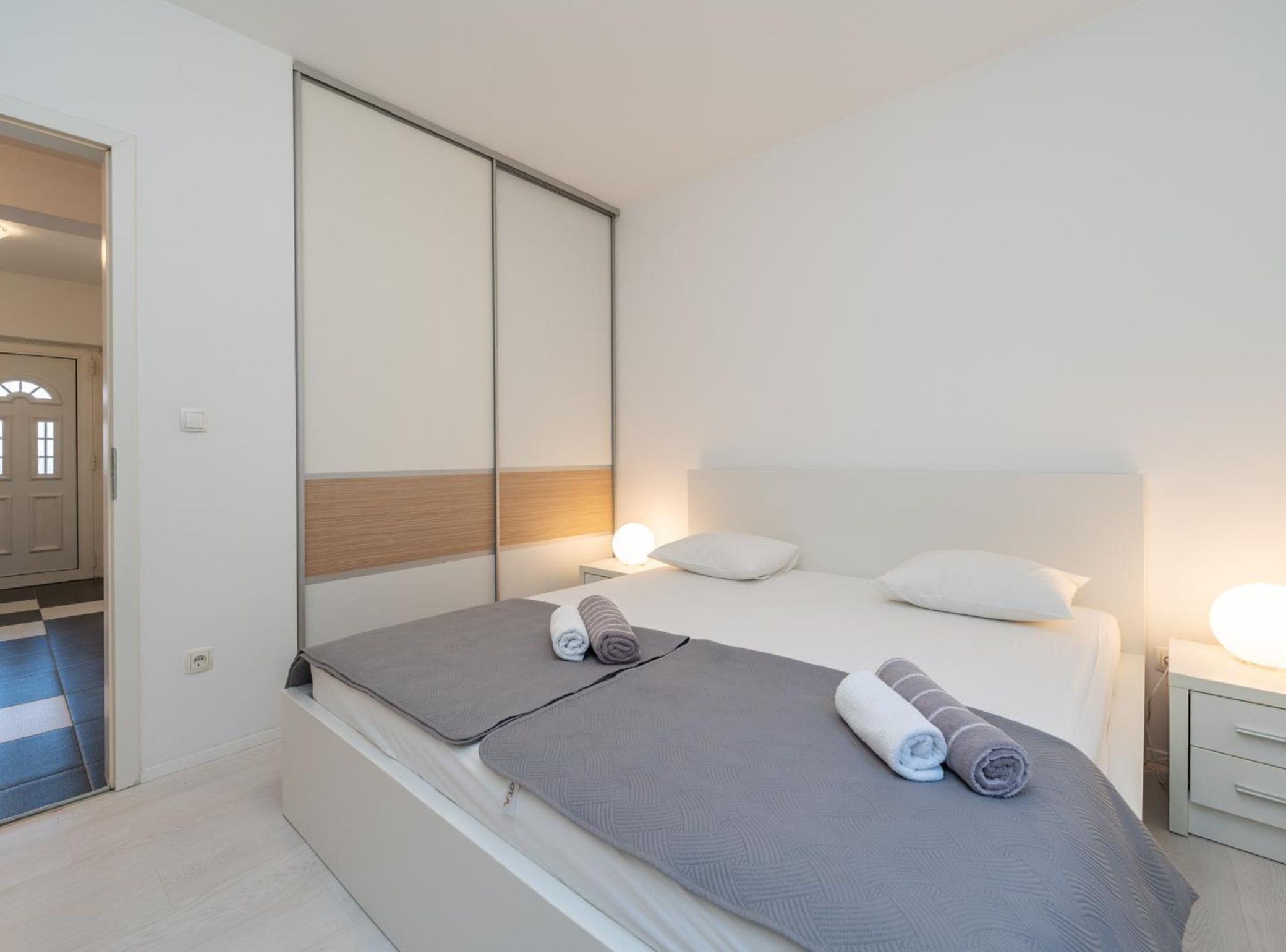 A modern bedroom with a bed, bedside tables, and a wardrobe.