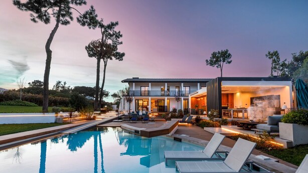 A modern house with a swimming pool, outdoor seating, and a patio area.