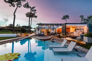 Ein modernes Haus mit Swimmingpool, Sitzgelegenheiten im Freien und einer Terrassenfläche.