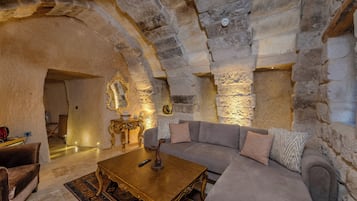 A stone-walled interior with a sofa, a coffee table, and a decorative mirror.