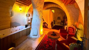 A spa room with a stone pillar, a bathtub, and red upholstered chairs. - Patina Cappadocia  (Nevsehir)