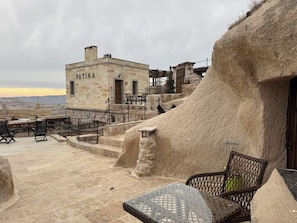 A rooftop terrace with stone steps, outdoor seating, and a view of the cityscape. - Patina Cappadocia (Nevsehir)