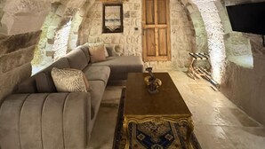 A cozy room with a stone ceiling, a wooden door, a sofa, and a coffee table. - Patina Cappadocia  (Nevsehir)