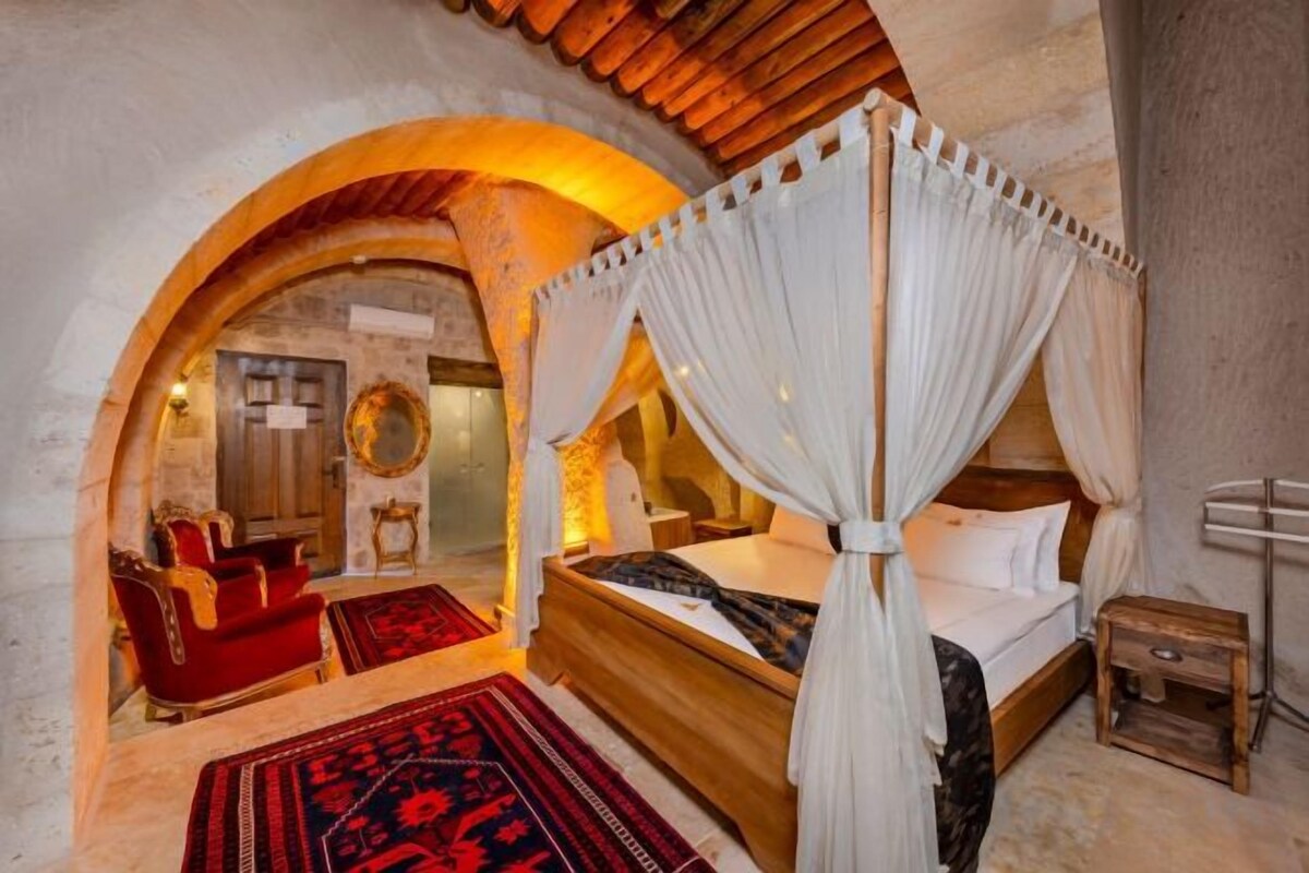 A bedroom with a four-poster bed, a red sofa, and a red and black patterned rug.