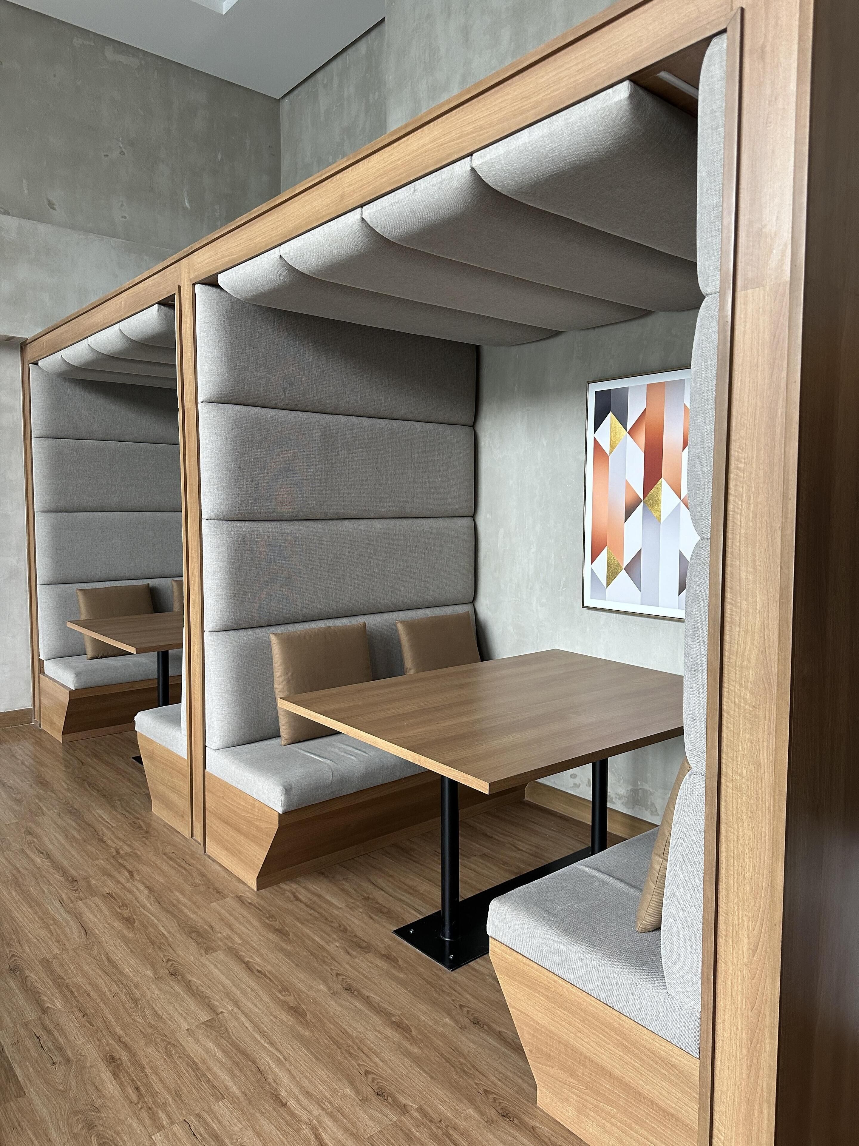 A modern seating area with built-in benches and tables, featuring a geometric wall art piece.