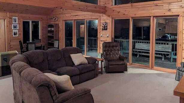 Un salón amplio con un sofá modular grande, un sillón reclinable y techo de madera.