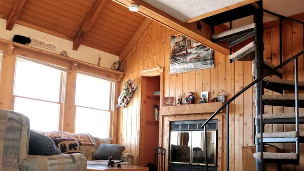 A cozy cabin interior with a wooden staircase, a fireplace, and a couch with patterned cushions. - 1BR cabin plus loft sleeps 5 fantastic views (Davis)