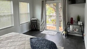 Ein Schlafzimmer mit einem großen Bett, einem Deckenventilator, einer Schiebetür zu einem Balkon und einem an der Wand befestigten Fernseher.