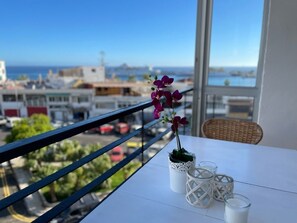 En balkon med en potteorkidé, en fletstol og et bord med et glas mælk og en vase.