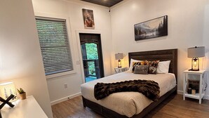 A bedroom with a large bed, a ceiling fan, a window with blinds, a small table with a lamp, and a rug. - 8 miles to Dollywood-Hot Tub-Game Room-King & Queen Beds-Sleeps up to 6 (Sevierville)