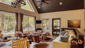 A spacious room with a wooden dining table, chairs, a sofa, and a ceiling fan. - 8 miles to Dollywood-Hot Tub-Game Room-King & Queen Beds-Sleeps up to 6 (Sevierville)