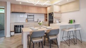 Una cocina moderna con armarios de madera, horno empotrado y comedor con mesa y sillas.