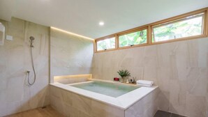 Un baño moderno con una bañera independiente, ducha y ventana que proporciona luz natural.