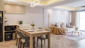 Una sala de estar moderna con comedor, un conjunto de sofás y una cocina equipada con refrigerador y microondas.