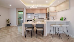 Una cocina moderna con comedor, armarios de madera y una isla central con taburetes de bar.