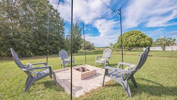 En terrasse med fire Adirondack-stole, en ildsted i mursten og lyskæder.