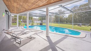 A covered outdoor swimming pool area with lounge chairs and a view of a backyard. - Weeki Wachee Pod


 (Spring Hill)