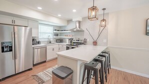 A modern kitchen with stainless steel appliances, a large island, bar stools, and pendant lighting. - Weeki Wachee Pod


 (Spring Hill)