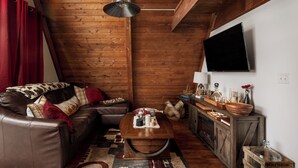 A cozy living room with a leather sofa, wooden coffee table, and a television mounted on the wall.
