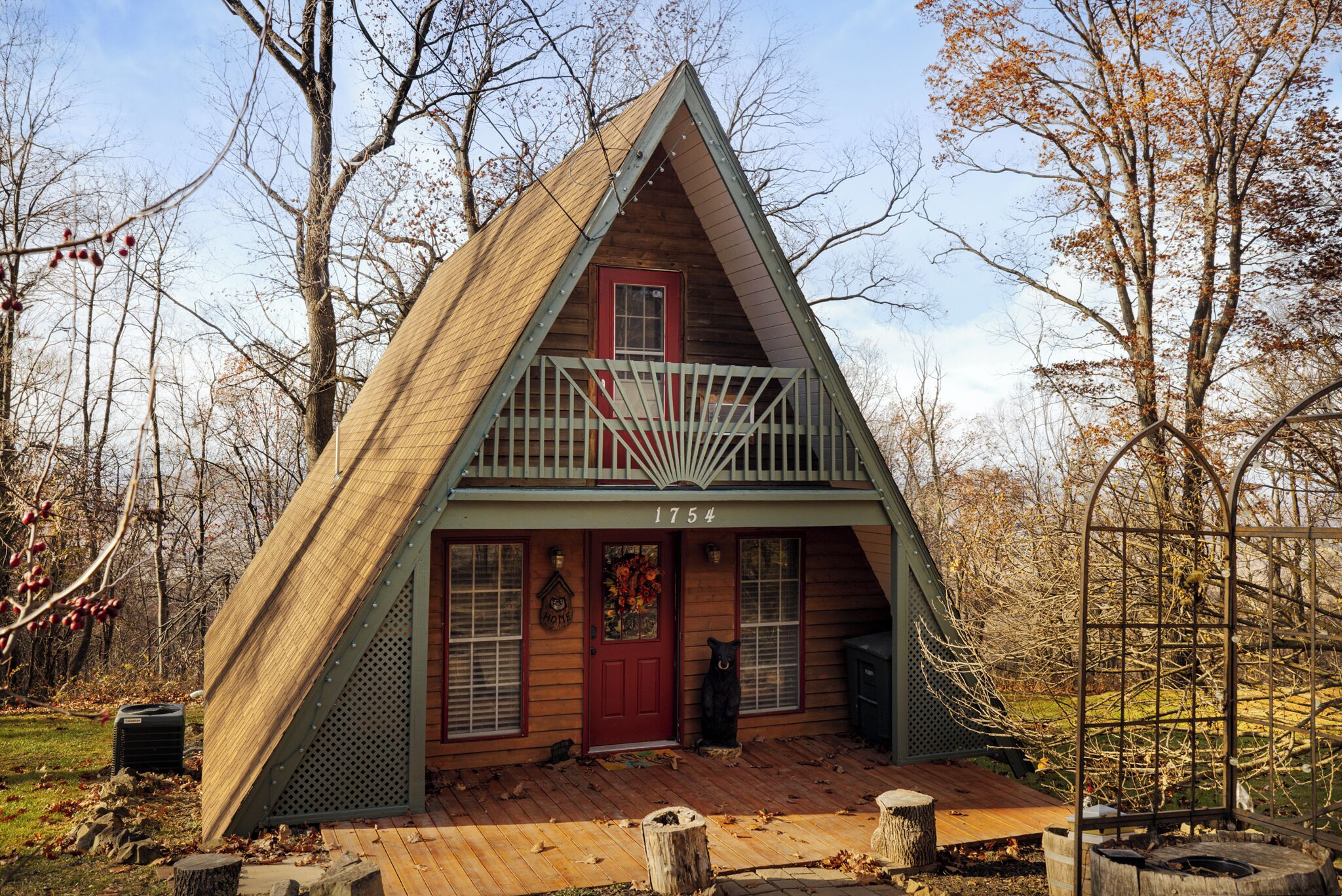 Une cabane en bois avec une porte rouge, un balcon et le numéro 1754 sur la façade.