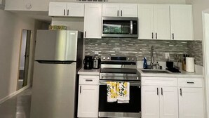 Una cucina moderna con mobili bianchi, elettrodomestici in acciaio inossidabile, una ventola a soffitto e uno schienale in piastrelle.