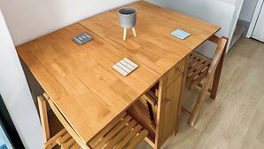 Una piccola scrivania in legno con due sedie, una tazza grigia e due targhette.