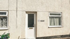 Un edificio a un piano con una porta e finestre bianche. Sopra la porta, una piccola insegna indica il nome della proprietà.