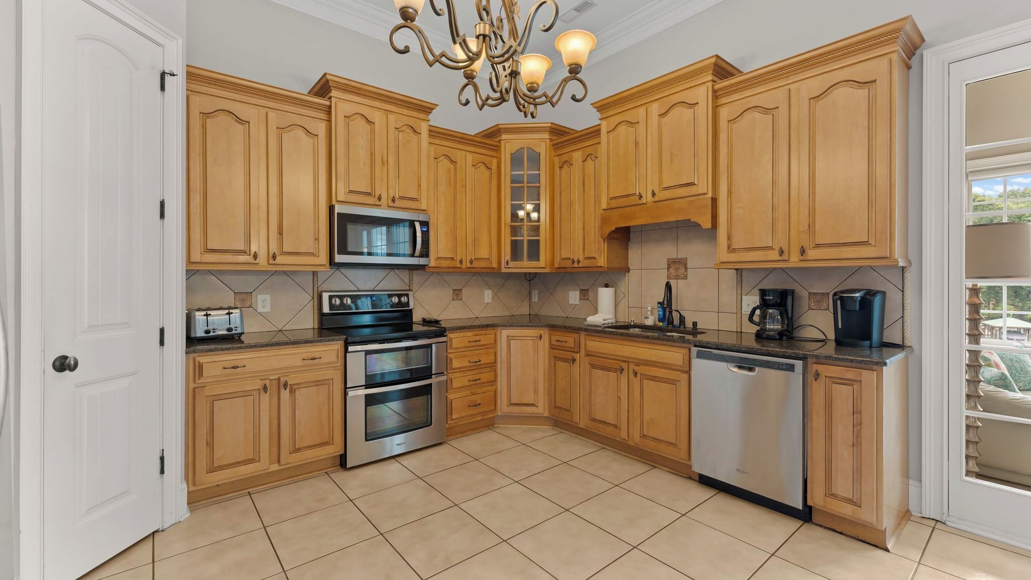 A kitchen with wooden cabinets, a microwave, a stove, a dishwasher, and a chandelier.