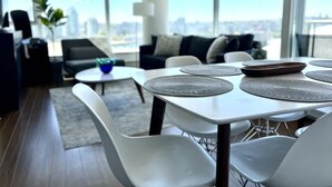 Un salon moderne avec un coin repas, de grandes fenêtres et une vue sur la ville.