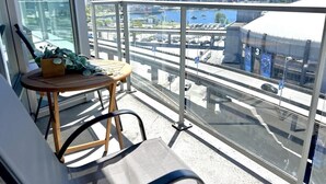 Un balcon donnant sur un paysage urbain, une table avec une chaise et une plante en pot.