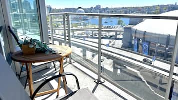 Un balcón con vistas a un paisaje urbano, una mesa con una silla y una planta en maceta.