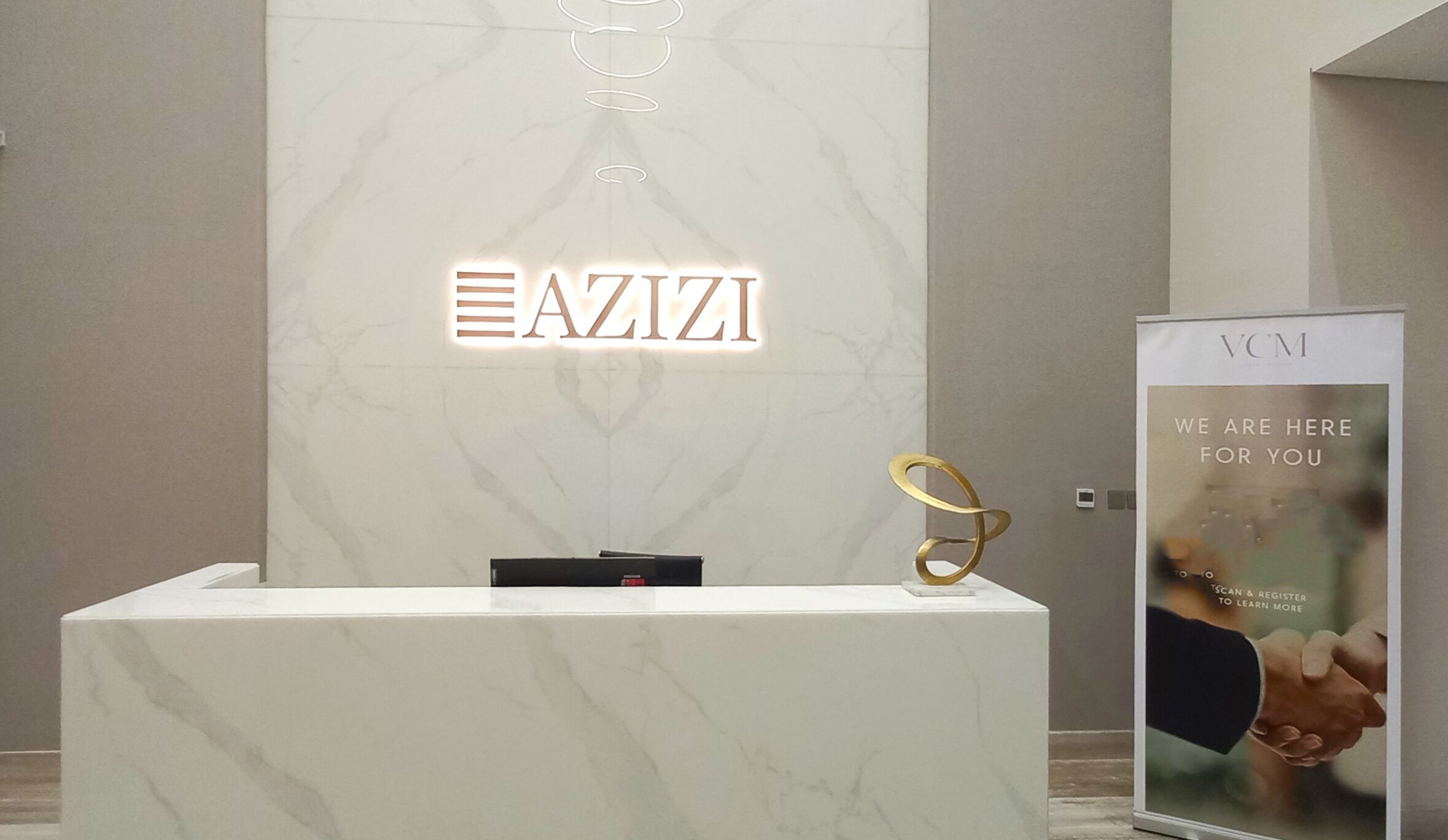 A reception desk with a marble top and a sign that reads "AZIZI".