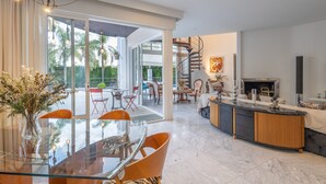 Un interior moderno con comedor, cocina y una escalera de caracol.