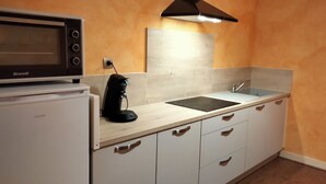 A compact kitchen with a Brandt microwave, a coffee maker, a sink, and a refrigerator. - Holiday Home 'Au Nid Douillet' with Shared Terrace, Shared Garden and Wi-Fi (Bourges)