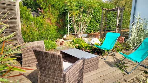 A wooden deck with wicker furniture and a blue chair. - Holiday Home 'Au Nid Douillet' with Shared Terrace, Shared Garden and Wi-Fi (Bourges)