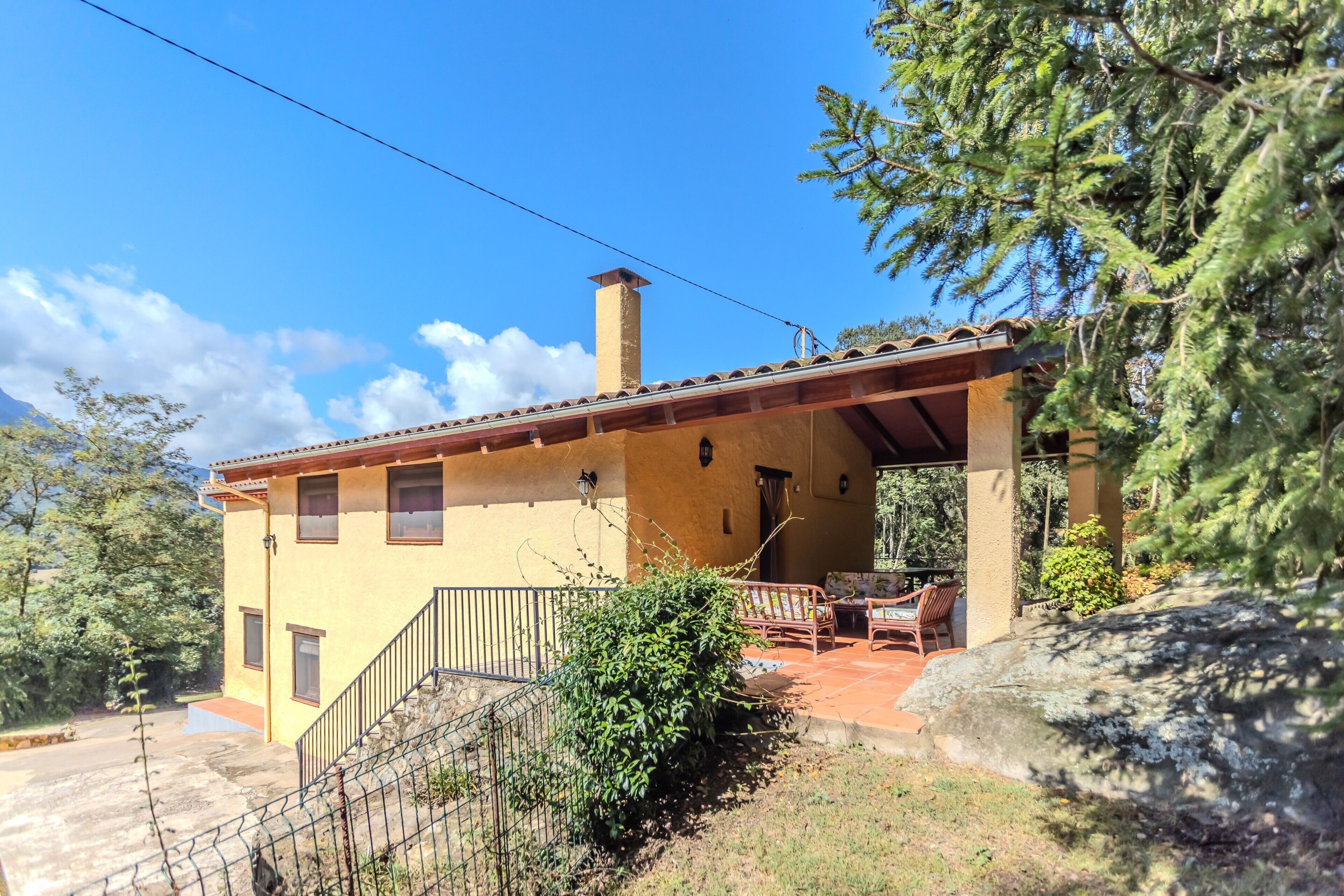 A two-story building with a patio area, a staircase, and a view of the surrounding landscape.