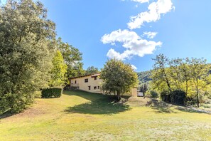 A house with a sloped roof, surrounded by trees and a clear sky. - Rural House 'Can Guidic' with Mountain Views, Private Pool and Wi-Fi (La Vall D' en Bas)