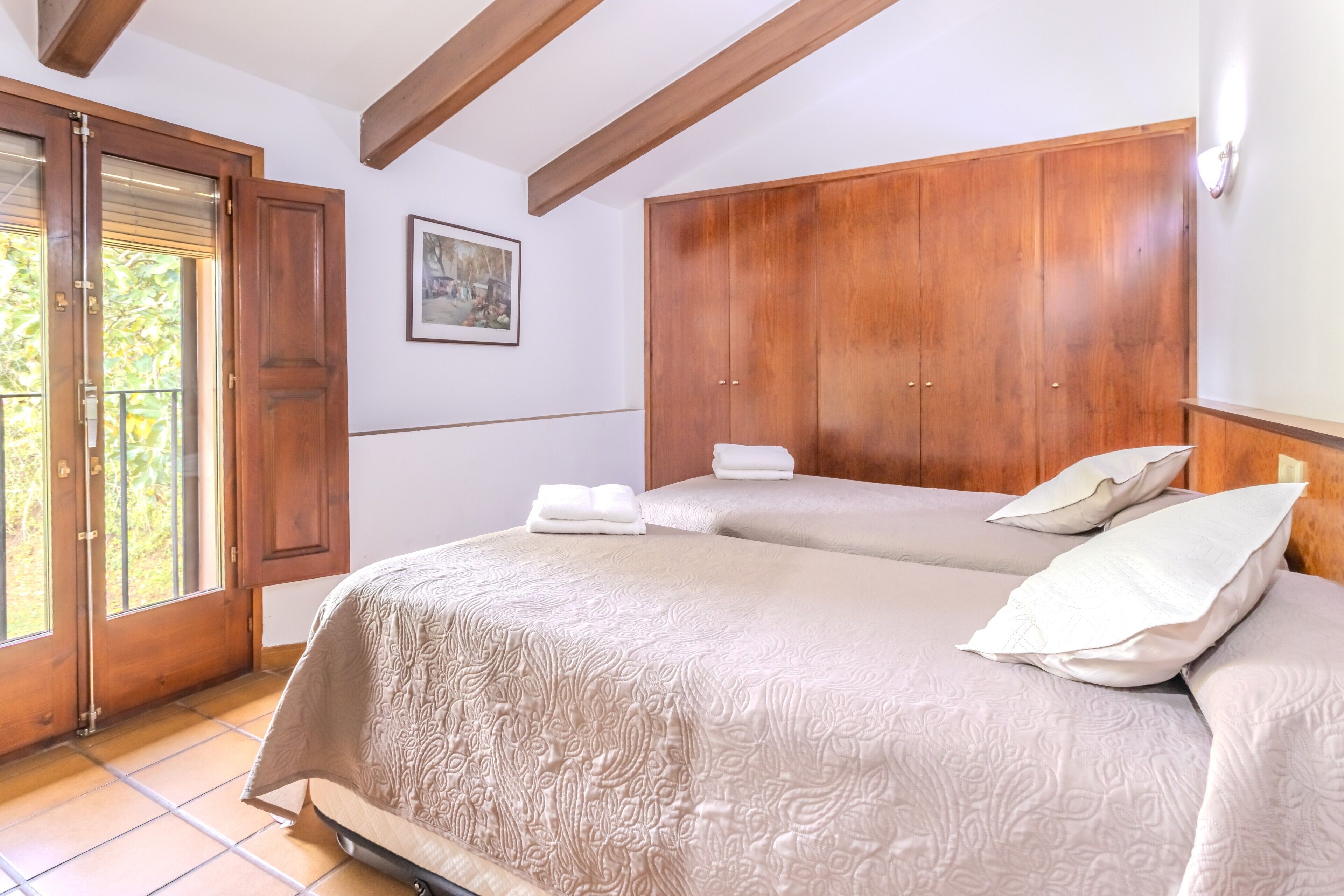 Un dormitorio con una cama grande, un armario de madera y una puerta que da a un balcón.