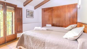 Un dormitorio con una cama grande, un armario de madera y una puerta que da a un balcón.
