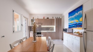 A modern kitchen with wooden cabinets, a dining table, and a large painting on the wall. - Villa 'La Collina' with Private Terrace, Wi-Fi and Air Conditioning (Galatone)