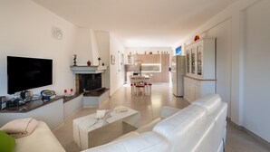 A modern living room with a flat-screen TV, a fireplace, and a dining area with a table and chairs. - Villa 'La Collina' with Private Terrace, Wi-Fi and Air Conditioning (Galatone)
