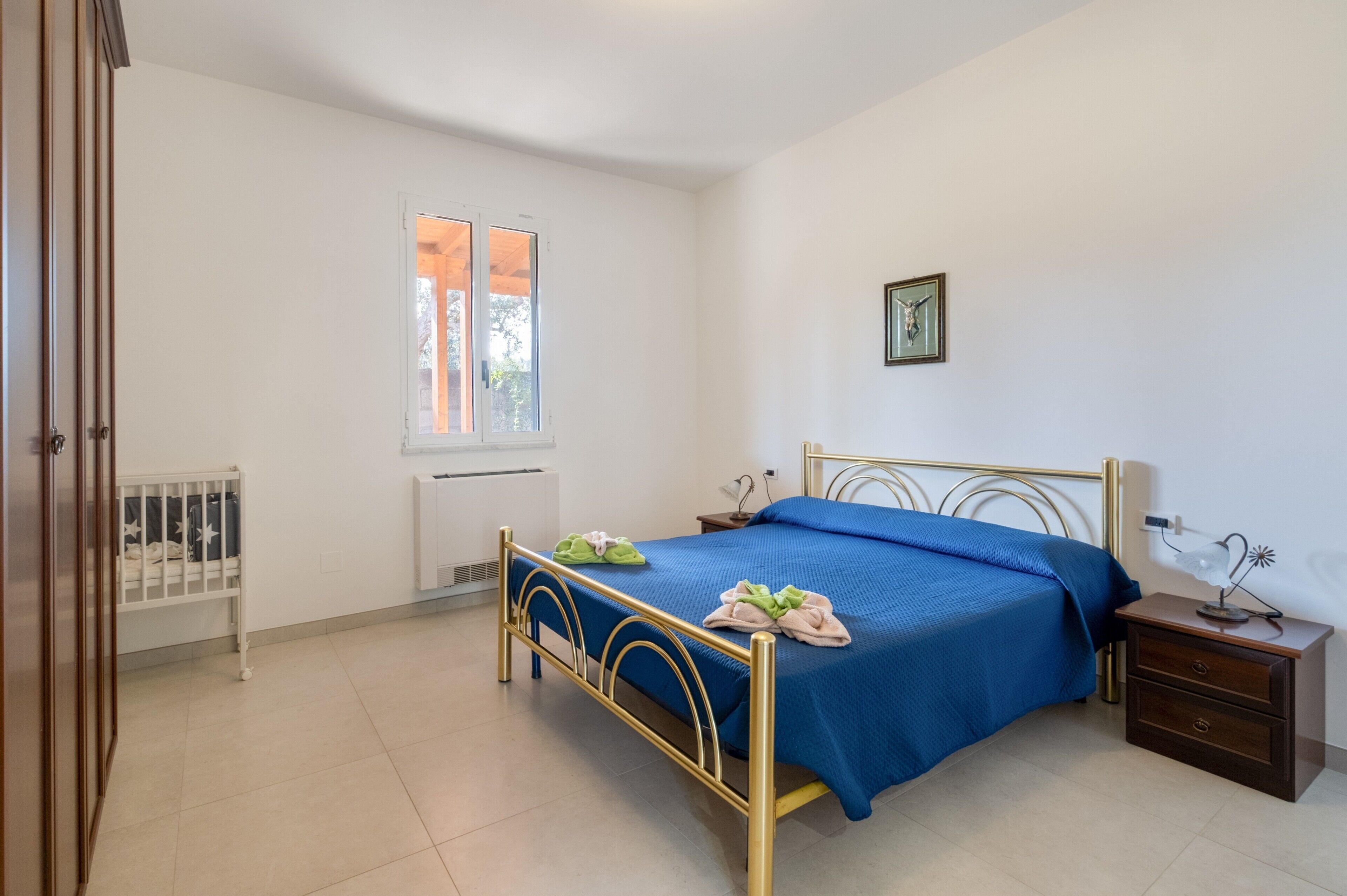 Una camera da letto con un letto, comodino, termosifone e culla.