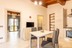 A modern kitchen with a dining area, a TV, and a clock on the wall.